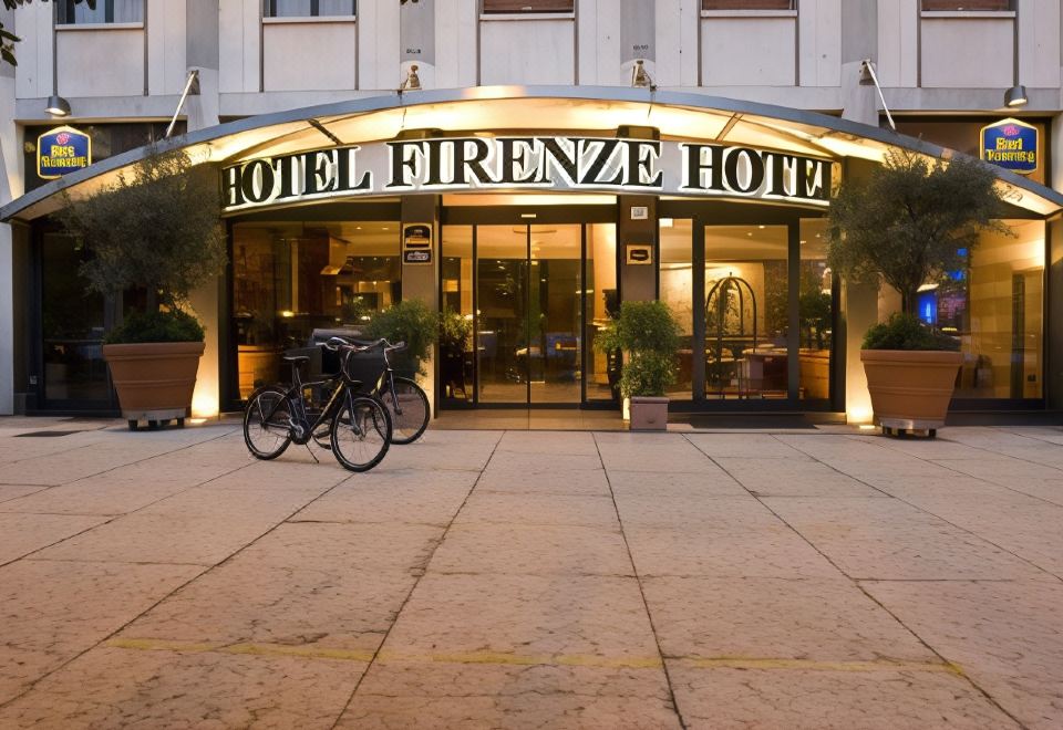 a hotel entrance with a large sign above the door , and two bicycles parked outside at Hotel Firenze