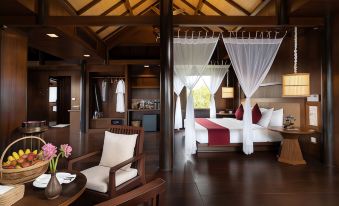 a luxurious bedroom with a large bed draped in a white canopy , surrounded by wooden furniture at Mane Hariharalaya