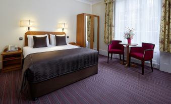 a large bed with a brown comforter is in the center of a room with purple carpet and two tables at The Abbey