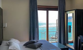 a modern hotel room with a large window offering a view of the sea , a comfortable bed , and blue flooring at Hotel la Lucertola