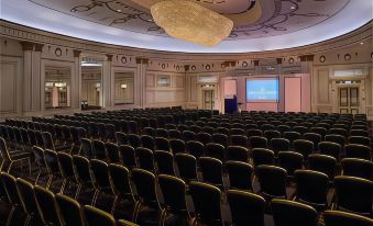 a large , empty conference room with rows of chairs and a screen at the front at The Midland Hotel