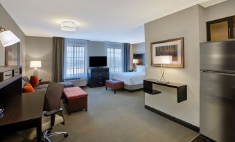 a modern hotel room with a comfortable bed , desk , and chairs , along with a tv and other amenities at Staybridge Suites Benton Harbor - ST. Joseph