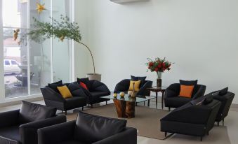 a modern living room with black leather furniture , including chairs and couches , arranged around a coffee table at Hotel Capital