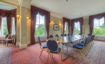 a large conference room with multiple chairs arranged in a semicircle around a long table at Makeney Hall Hotel