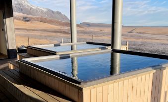 a hot tub is seen in a wooden enclosure with a mountain and valley view at Fosshotel Glacier Lagoon