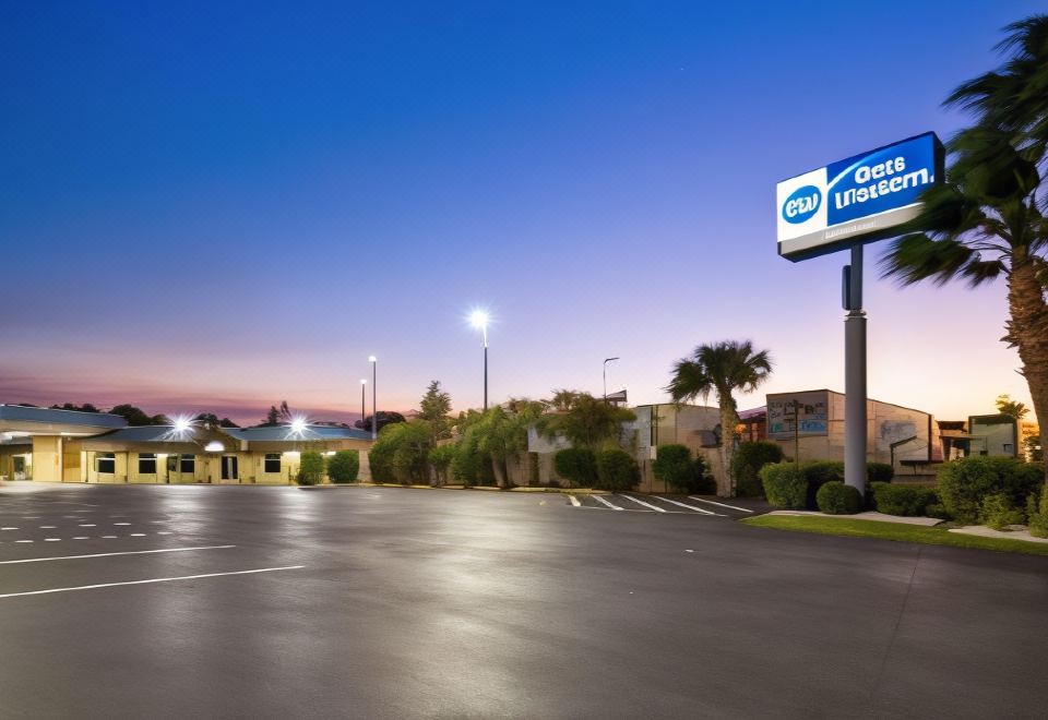 "a parking lot with a large , blue sign reading "" quality inn "" in front of a motel" at Ramada by Wyndham Cocoa