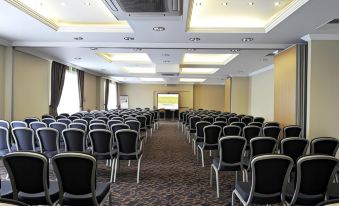 a conference room with rows of chairs arranged in a semicircle , and a projector on the wall at Link Hotel