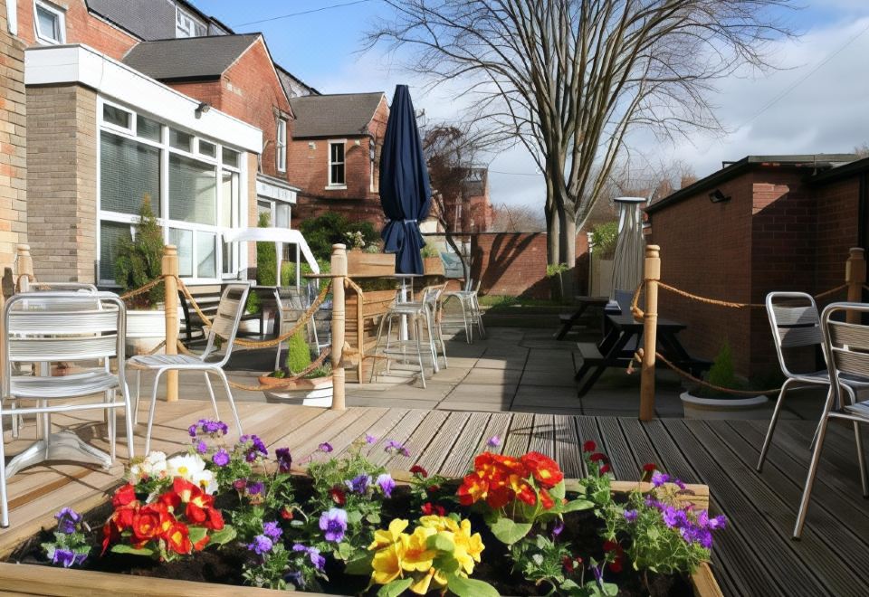 a beautiful outdoor patio with wooden flooring , flowers , and a blue umbrella , surrounded by houses at Caledonian Hotel