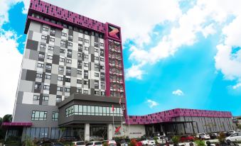 a modern building with a red and gray exterior , surrounded by cars parked in front of it at Grand Zuri Dumai