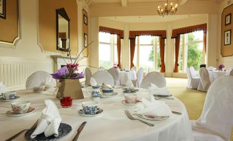 a dining room with white tablecloths , dining chairs , and a table set for a formal event at The Atholl Palace