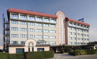 a large hotel building with a red roof and many windows , located in a city setting at B&B Hotel Bologna