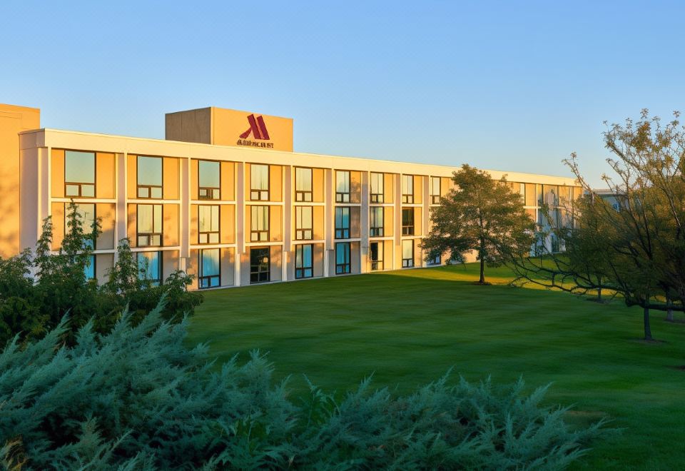 "a large building with a red letter "" a "" on it is surrounded by a green lawn and trees" at Washington Dulles Airport Marriott