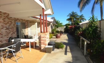 a patio area with several chairs and a dining table , surrounded by a fence and surrounded by plants at Redland Bay Motel