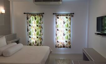 a bedroom with two floral curtains and a bed , giving it a cozy and inviting atmosphere at Saraburi Garden Resort