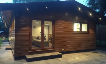 a small wooden house with a garage door and a door that leads to a bedroom at Shellow Lane Lodges