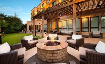 a well - lit outdoor patio area with a fire pit surrounded by chairs and tables , creating a cozy atmosphere at Courtyard Lufkin