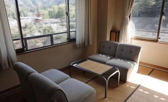 a living room with two gray couches , a wooden coffee table , and a view of mountains through a large window at Jukeiso