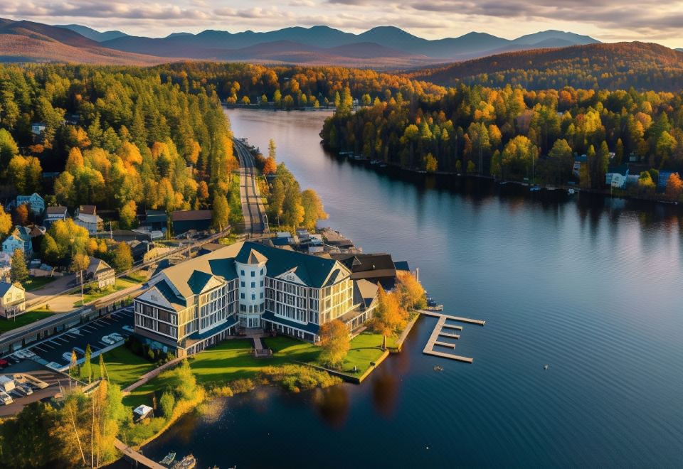 an aerial view of a lake surrounded by trees , with a large building on the shore at Saranac Waterfront Lodge, Trademark Collection by Wyndham