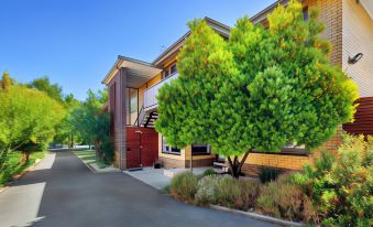 a brick building with trees in front of it , creating a serene and inviting atmosphere at Lake Wendouree Luxury Apartments