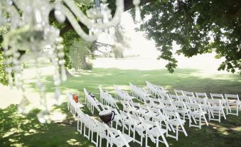 a white lawn set up for a wedding ceremony , with rows of chairs arranged in an open field at Quamby Estate