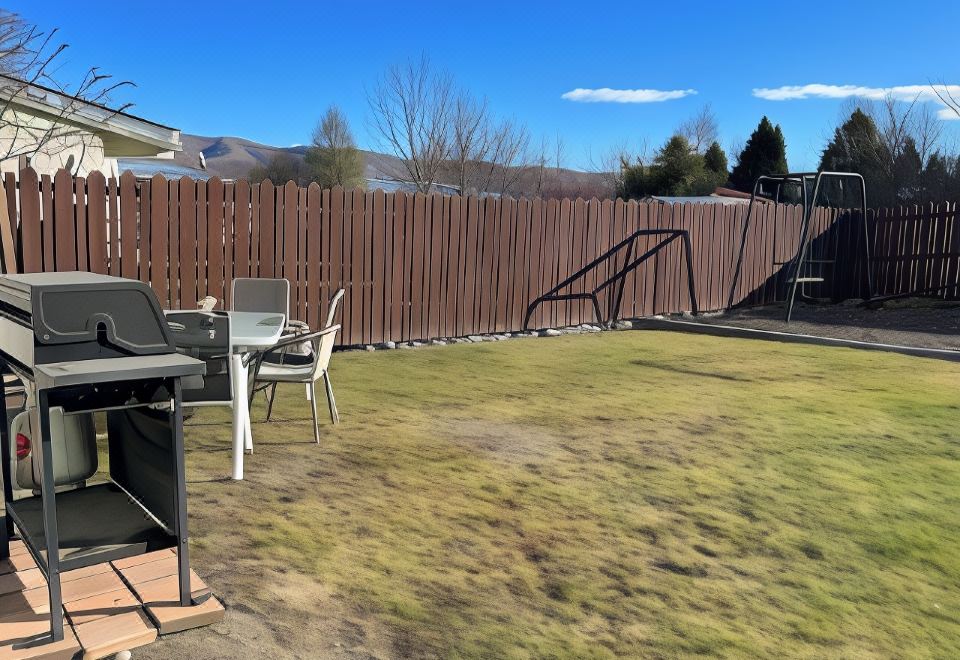 a backyard with a wooden fence , outdoor furniture , and a view of the mountains in the background at Pinewood Motels