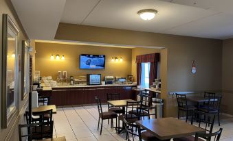 a dining area with tables , chairs , and a tv mounted on the wall , providing a comfortable atmosphere for guests at Wingate by Wyndham Clearfield