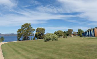a serene landscape with trees and grass , set against a clear blue sky and a distant building at Riverfront Motel & Villas
