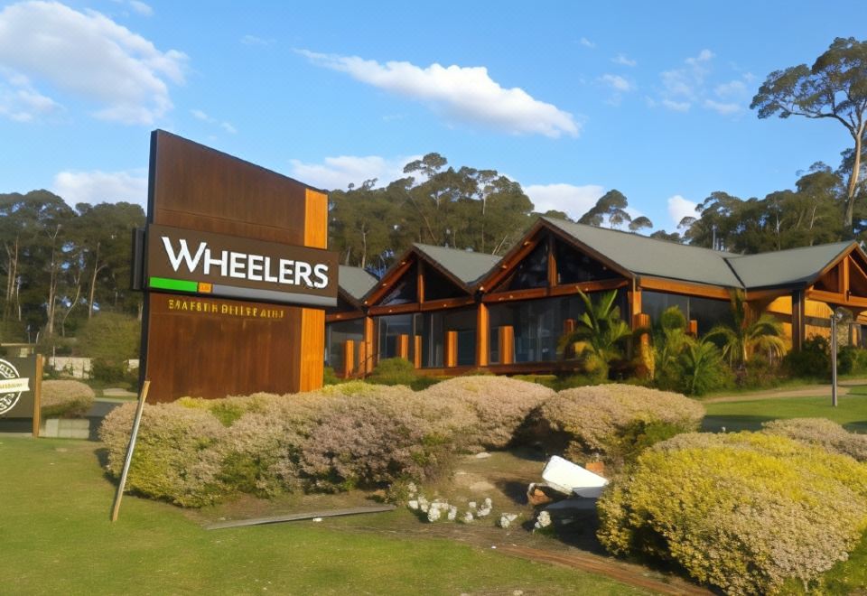 "a large building with the sign "" wheelers "" on it , surrounded by greenery and other buildings" at Fairway Motor Inn