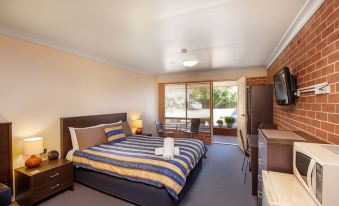 a bedroom with a bed , dresser , and tv . also a chair in the room , possibly a hotel room at Lake Macquarie Motor Inn