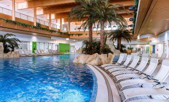 an indoor swimming pool with a large artificial island , surrounded by palm trees and lounge chairs at Hotel Diamante