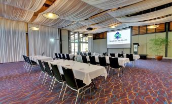 a conference room set up for a meeting , with tables and chairs arranged in rows at Kingfisher Bay Resort