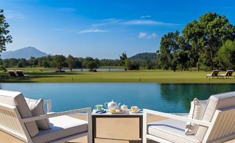 a beautiful outdoor setting with a table , chairs , and tea cups on a deck overlooking a lake and golf course at Jetwing Lake