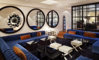 a modern living room with blue sofas , black tables , and large round mirrors on the walls at Hotel Pulitzer Buenos Aires