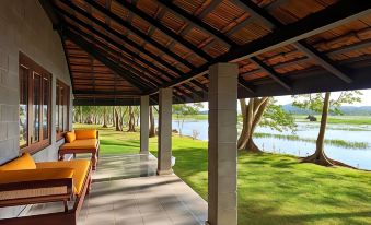 a covered porch overlooking a grassy field and a body of water , creating a serene atmosphere at Habarana Village by Cinnamon