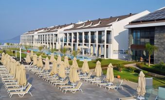 a large , white building with multiple balconies and umbrellas on the terrace , set against a clear blue sky at Jiva Beach Resort - Ultra All Inclusive