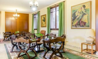 a dining room with wooden chairs and tables , green curtains , and paintings on the wall at Hotel Mora