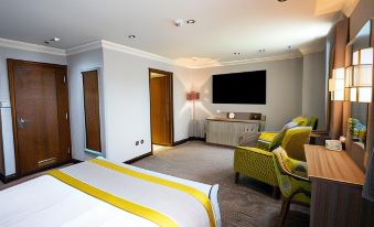 a modern hotel room with a bed , couch , and tv , decorated in white and yellow colors at Best Western Plus Pastures Hotel