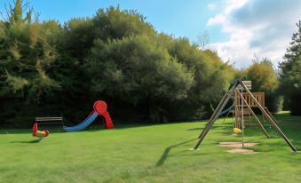 a sunny day in a park with a playground , a slide , and a swing set at Lagrange Vacances le Hameau de Peemor PEN