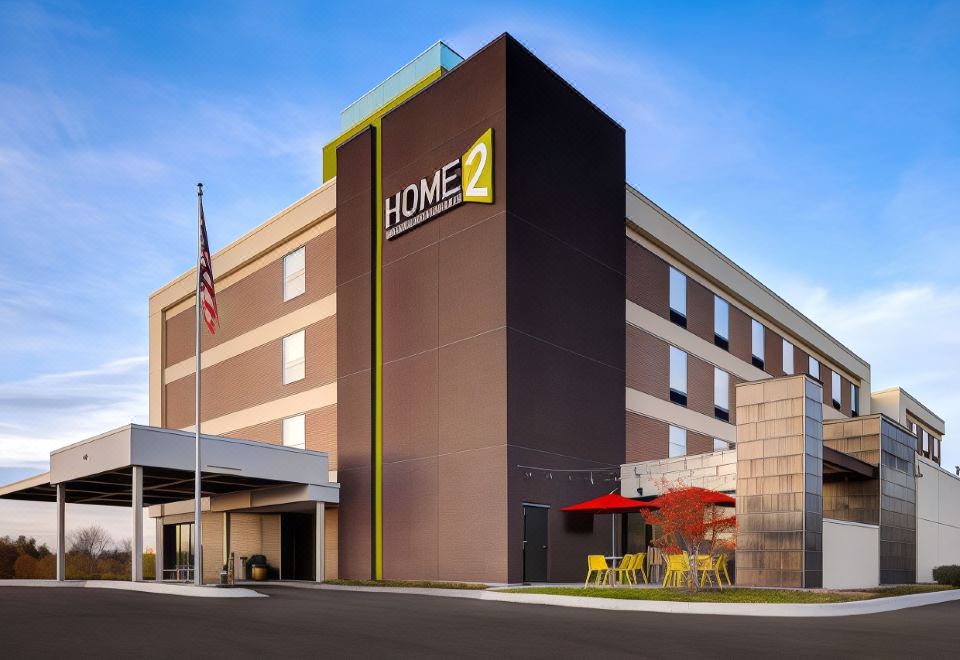 "a modern hotel with a brown and black exterior , featuring a yellow sign that says "" home 2 ""." at Home2 Suites by Hilton Dekalb