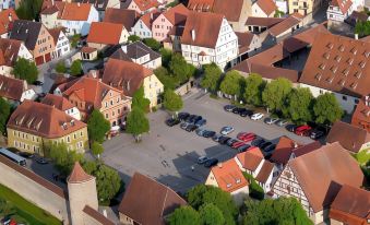 aerial view of a small european town with red roofed buildings and a parking lot filled with cars at Akzent Hotel Schranne