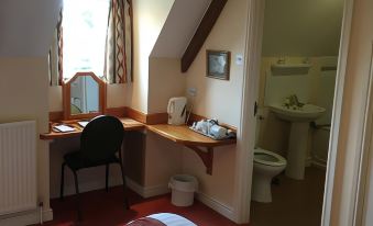 a hotel room with a bed , desk , and chair , as well as a bathroom visible through an open door at Malt House