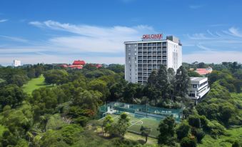 "a large white building with the name "" daloma "" on it , surrounded by trees and green grass" at Delonix Hotel Karawang