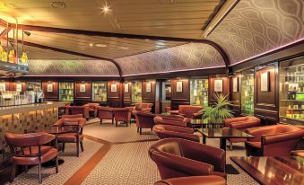 a modern lounge area with red leather chairs and tables , green plants , and a long bar at Harvey's Point