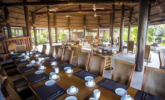a dining room with a large table set for a formal meal , surrounded by chairs and a chandelier at Sinalei Reef Resort & Spa