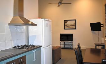 a kitchen with a stove , refrigerator , and microwave is shown next to a living room with a television at Seymours on Lydiard