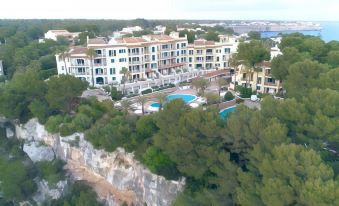 aerial view of a beach resort with multiple buildings and a swimming pool surrounded by trees at Aparthotel Ona Cala Pi Club