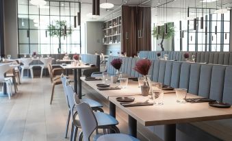 a restaurant with white tables and blue chairs , surrounded by windows and large windows on the walls at Hotel Odeon