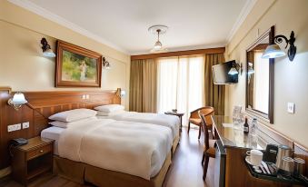 a hotel room with two beds , a desk , and a window , decorated with wooden furniture and a window at Semeli Hotel