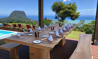 a dining table set for a meal , with a view of the ocean in the background at Chalets Chamarel