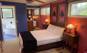 a large bed with a black and white comforter is in the center of a room with purple walls at Tambaridge Bed & Breakfast